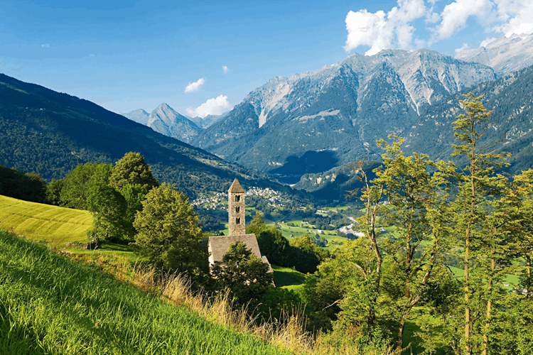 Paesaggio della Valle di Blenio con chiesa storica e montagne alpine in Ticino